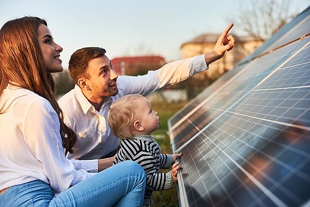 Familie mit Kleinkind betrachtet eine große Solaranlage im Freien